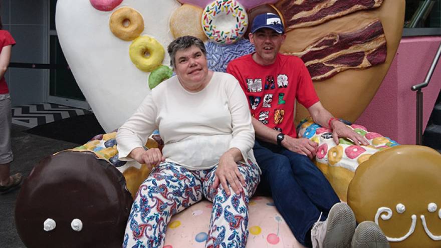 Two people sat on giant chair decorated with sweets and cookies in theme park