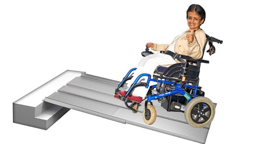 Woman using an electric wheelchair to move up a ramp.