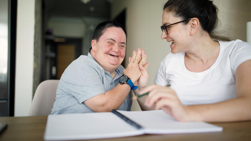 A woman high-fiving her young female student after getting some correct on her studies. 