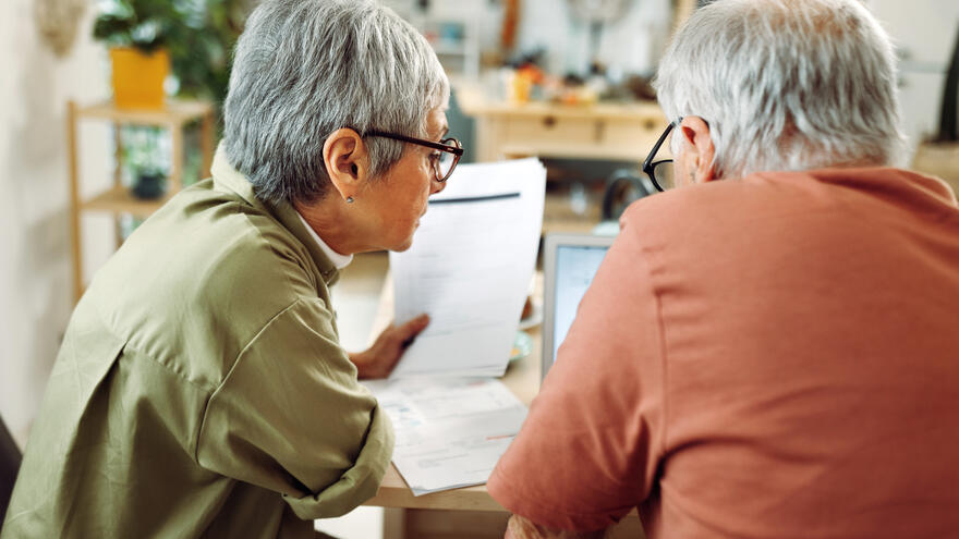 A man and a women reviewing and looking over paperwork together. 