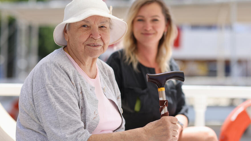 A older lady sat together with her adult daughter outside in the summer sun. 