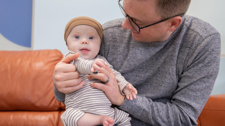 An image of a father holding and supporting his little baby.