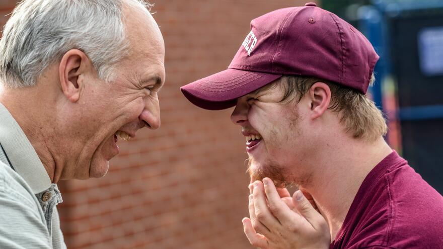 A father and son stood opposite each other affectionately smiling and laughing together.
