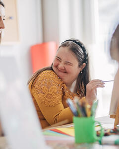 A girl enjoying painting at her art class with her mentor. 