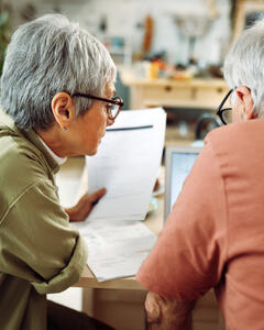 A man and a woman sat looking through and reviewing paperwork. 